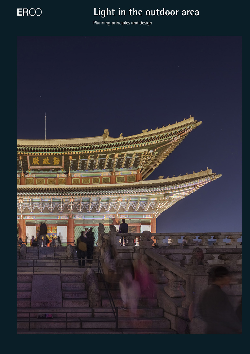 Illuminated palace with curved roof and visitors on steps.